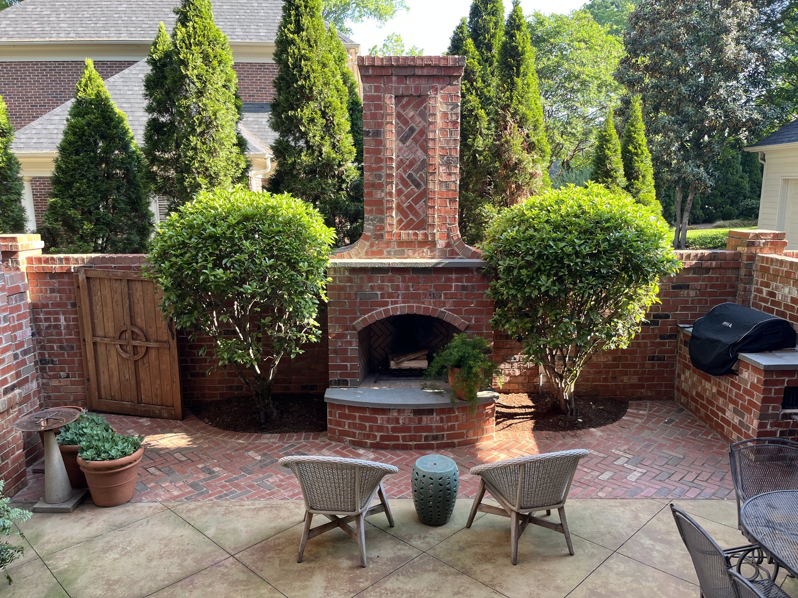 An outdoor courtyard with brick hearth and topiaries